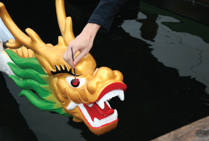 Hand reaching down to paint the eye on a dragon boat head