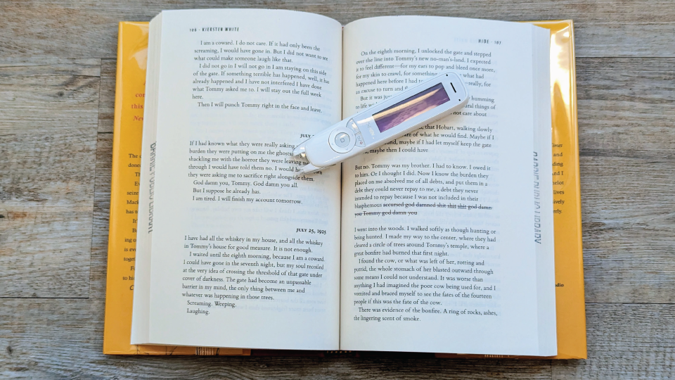 Hand holding C-PEN Reader Pen over book