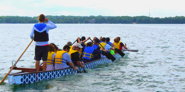 Multiple people in a long Dragon Boat, paddling on Lake Simcoe.
